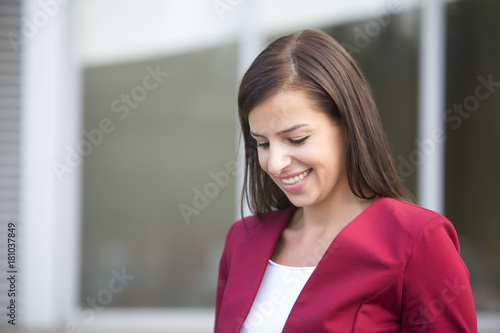 Young businesswoman in red blazer using mobile phone outdoor