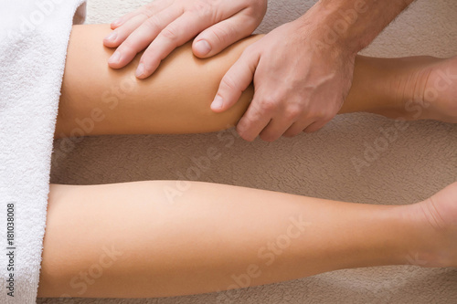 Fototapeta Naklejka Na Ścianę i Meble -  Masseur hands doing massage on young woman legs in the spa beauty salon. Body care concept.