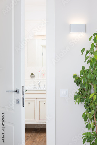 Modern wall lamp, bright white interior. The door ajar to the bathroom photo