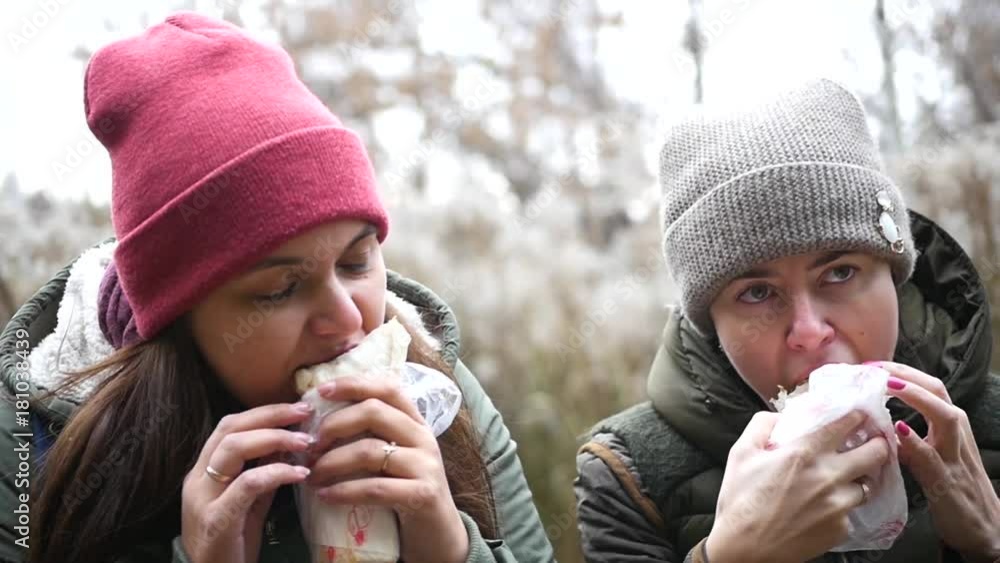 Two hungry girls in a hat sit in the park and eat a delicious and juicy shawarma. HD, 1920x1080, slow motion Two hungry girls in a hat sit in the park and eat a delicious and juicy shawarma. HD, 1920x1080, slow motion