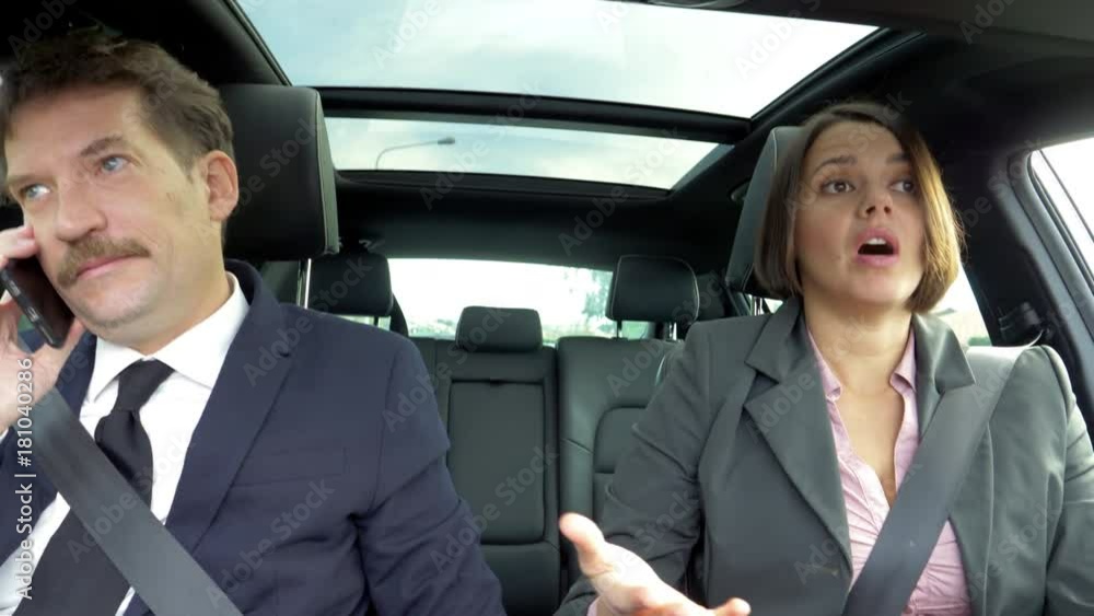 Business man and woman driving car discussing about deal on the phone Business man and woman driving car discussing about deal on the phone