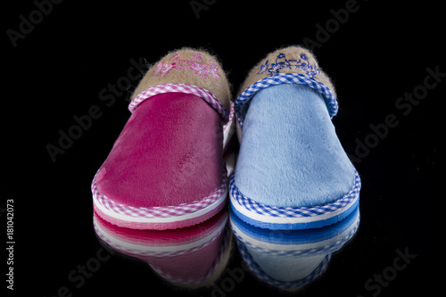 Female pink and blue slipper on black background, isolated product, comfortable footwear.
