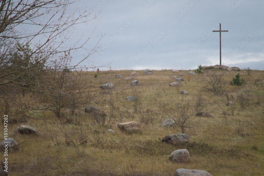 Peasant wooden cross on the mountain near the river bank, lake.