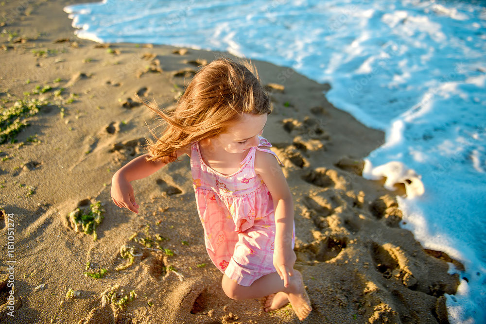 beautiful little girl in a dress is running and playing on the beach. beautiful little girl in a dress is running and playing on the beach.