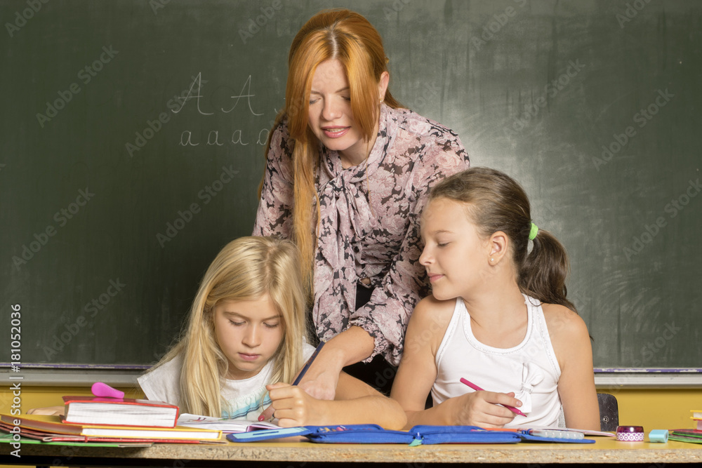 Female teacher helping kids in exercise Female teacher helping kids in exercise