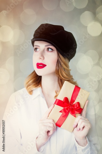 Young redhead woman in hat holding christmas gift box