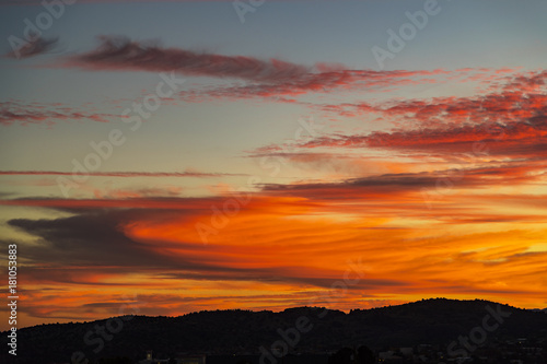 super orange clouds during sunset over a small mountain range