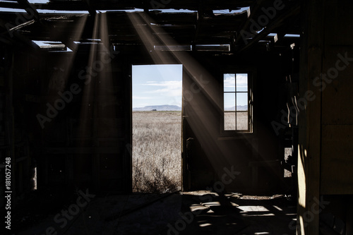 Wood frame room, abandoned and disintegrating, sunlight shining through cracks
