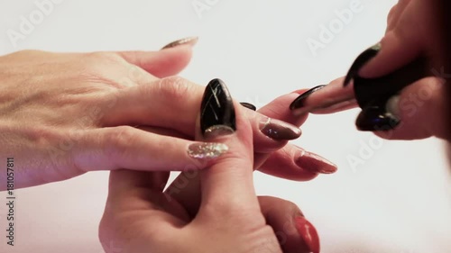 The manicurist makes the girl's nails on her right hand with a brown lacquer. Close-up.