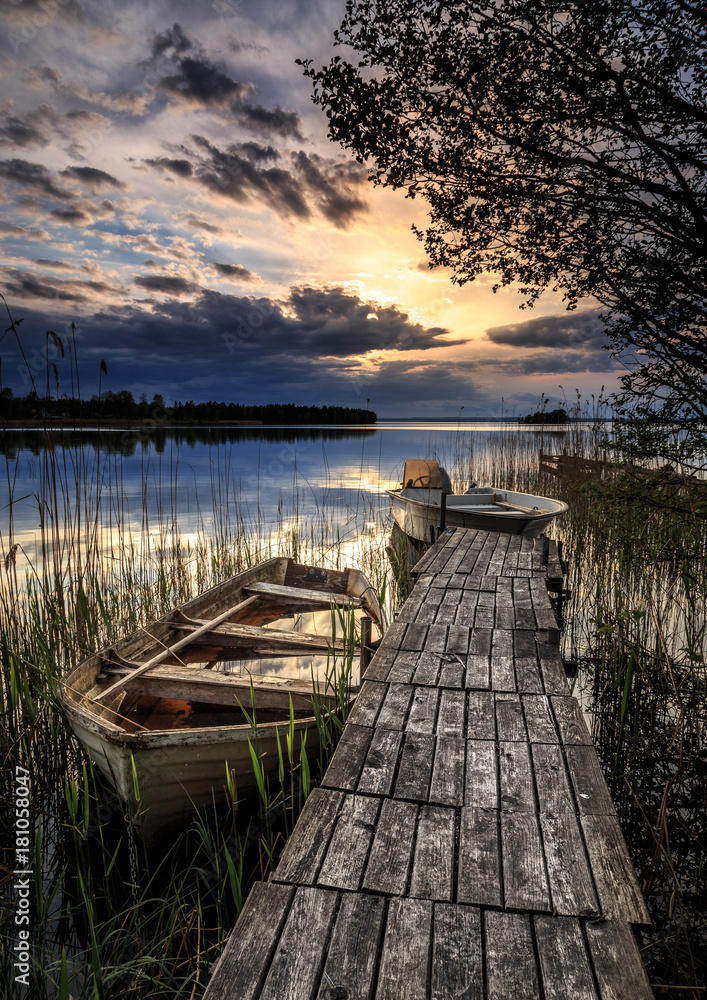 small boats at a wooden jetty with sunset in the background