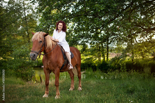 Beautiful woman is riding a horse. Summer meadow. © dinachi