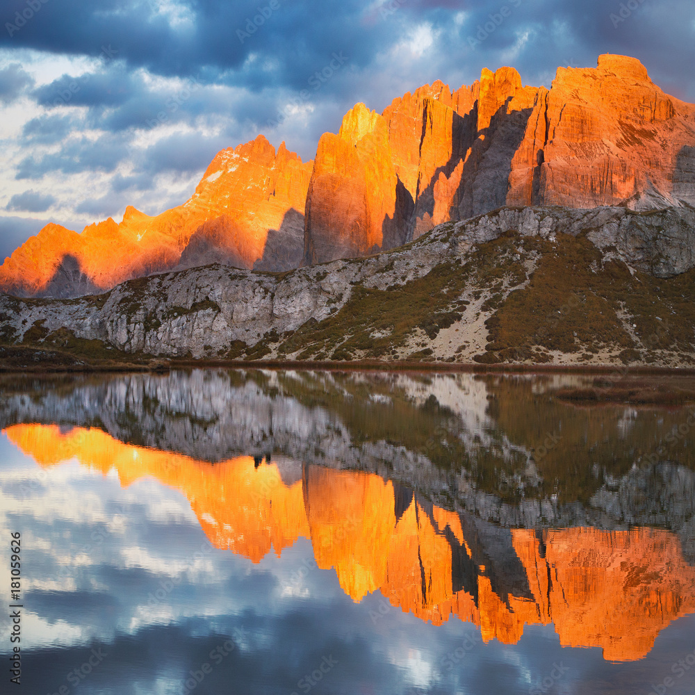 Evening on Laghi dei Piani (Lakes Piano) with mountains in sunlit reflected in smooth surface lake water, Southern Tyrol, Dolomites, Tre Cime di Lavaredo National Park, Italy. Enrosadira.
