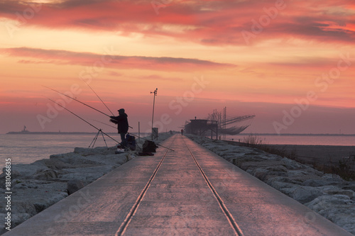 Fishermen at dawn along the pier of Sottomarina, Chioggia, venetian lagoon, Italy photo