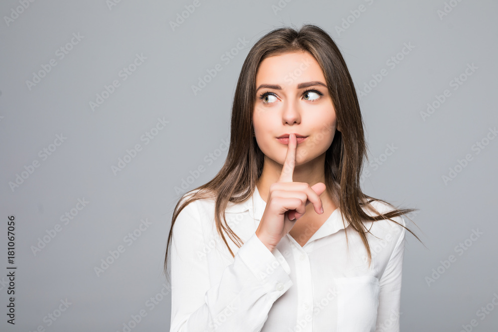 Pretty girl making silence gesture over grey background Pretty girl making silence gesture over grey background