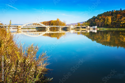Fototapeta Naklejka Na Ścianę i Meble -  Bridge in Piestany (Slovakia), Vah river, blue sky, colorful autumn