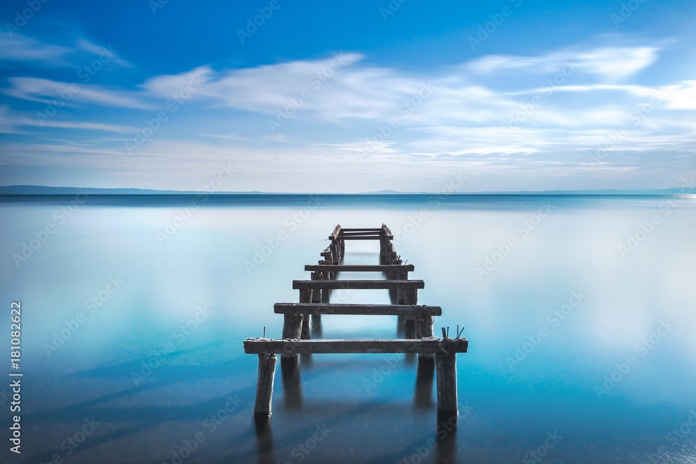 Wooden pier or jetty remains on a blue lake. Long Exposure. Wooden pier or jetty remains on a blue lake. Long Exposure.