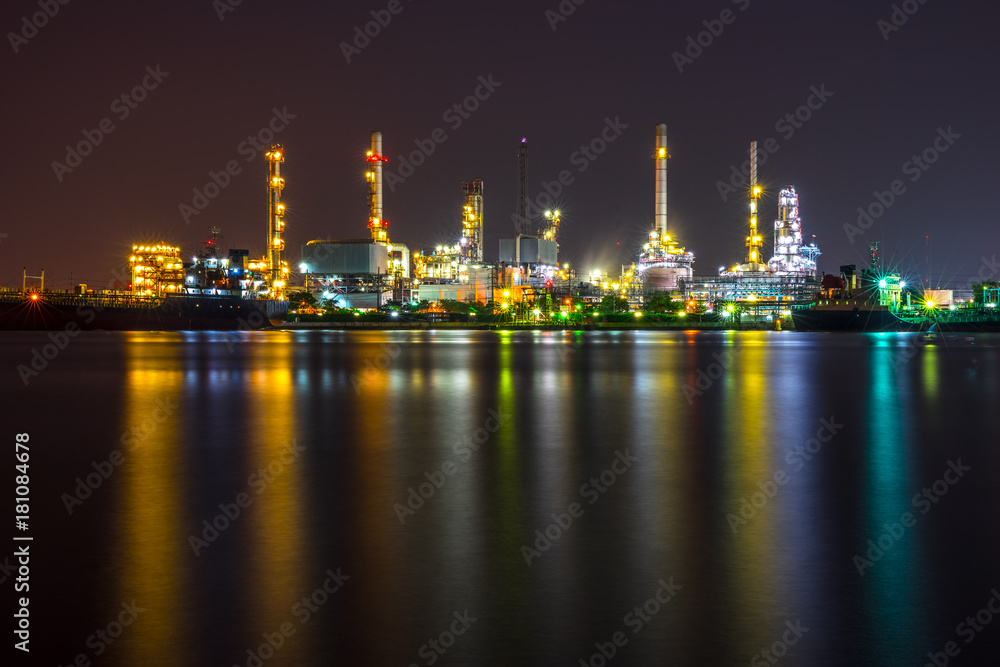Oil refinery, tanker ship and petrochemical plant at night beside Chao Phaya river, Thailand. Colorful light reflection.