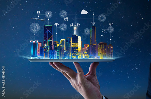 Waiter hand holding an empty digital tablet with Smart city with smart services and icons, internet of things, networks and augmented reality concept , night scene . photo