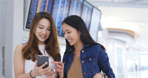 Photography Girl friends checking time schedule on mobile phone in Hong Kong airport