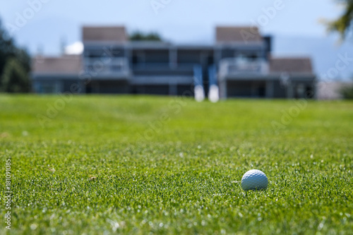 Golf ball in the fairway with out of focus building in the background 