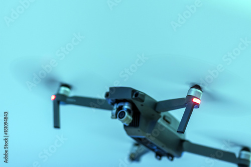 A blurry black unmanned radio-controlled drone on a blue background. Shallow depth of field.