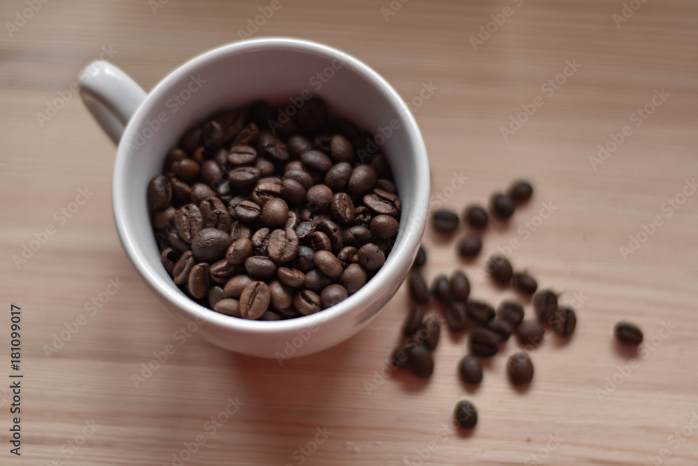 Cup full of coffee beans at wooden background/ top view Cup full of coffee beans at wooden background/ top view