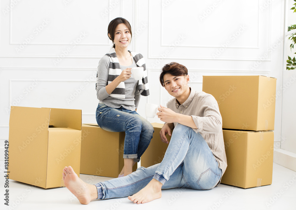 young couple Carrying Boxes Into New Home and drinking coffee young couple Carrying Boxes Into New Home and drinking coffee