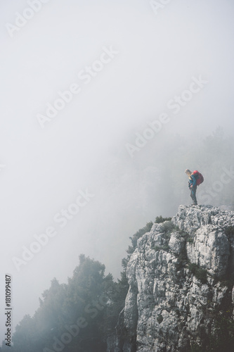 Tourist with backpack on foggy rocky cliff mountains Travel Lifestyle hiking adventure concept vacations outdoor exploring wild nature