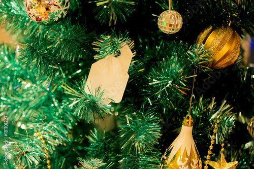 Christmas tree decorated with beautiful golden ornaments and empty card hanging - to insert any text.