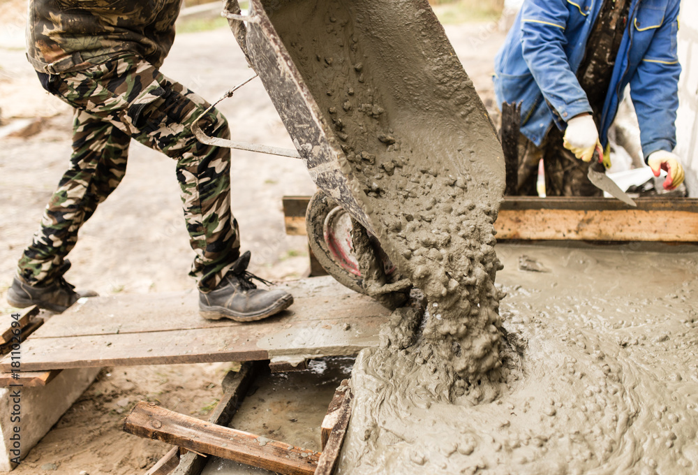worker pours concrete mortar on a construction site