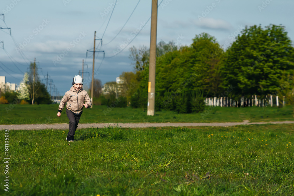Fototapeta premium Handsome boy of six years playing, jumping, running, smiling in the park. Place for text