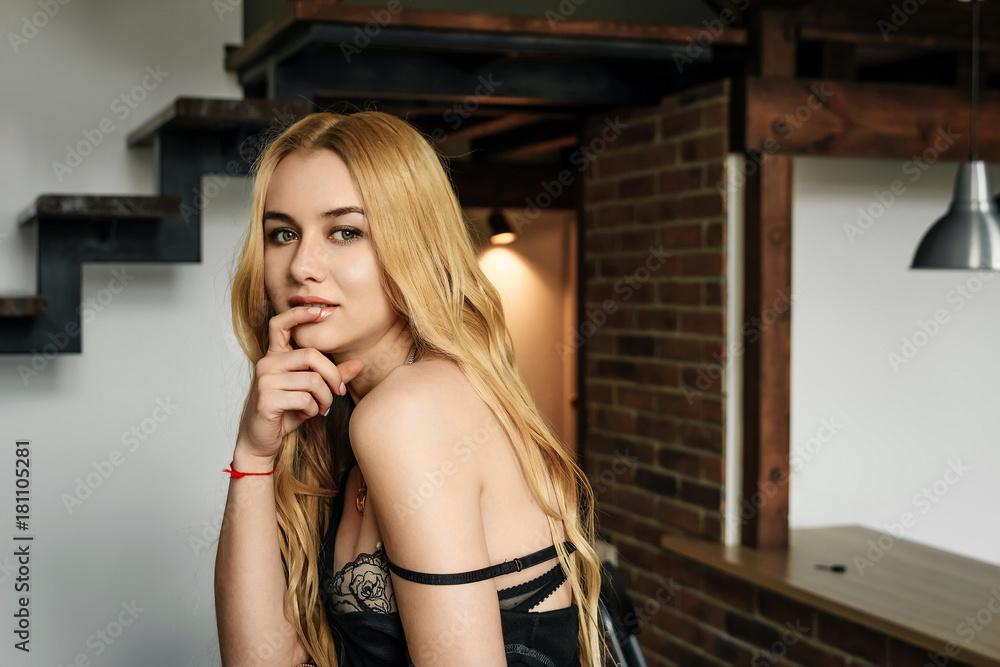 Beautiful blond girl in a black dress in an interior, sexy look Beautiful blond girl in a black dress in an interior, sexy look