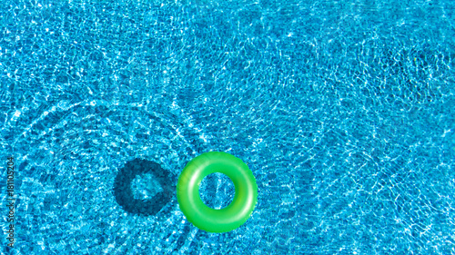 Aerial view of colorful inflatable ring donut toy in swimming pool water from above, family vacation concept background 