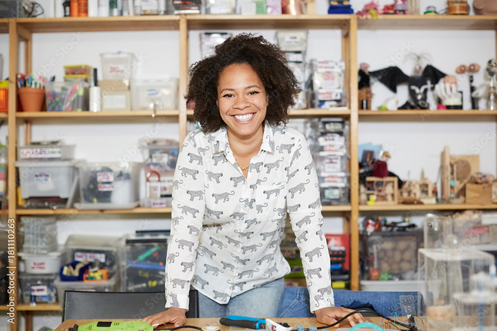 Portrait of confident female technician standing against shelf at workshop Portrait of confident female technician standing against shelf at workshop