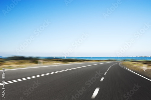 empty asphalt road with blue sea in blue sky