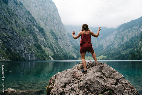Young woman standing on rock looking at beautiful and misty lake