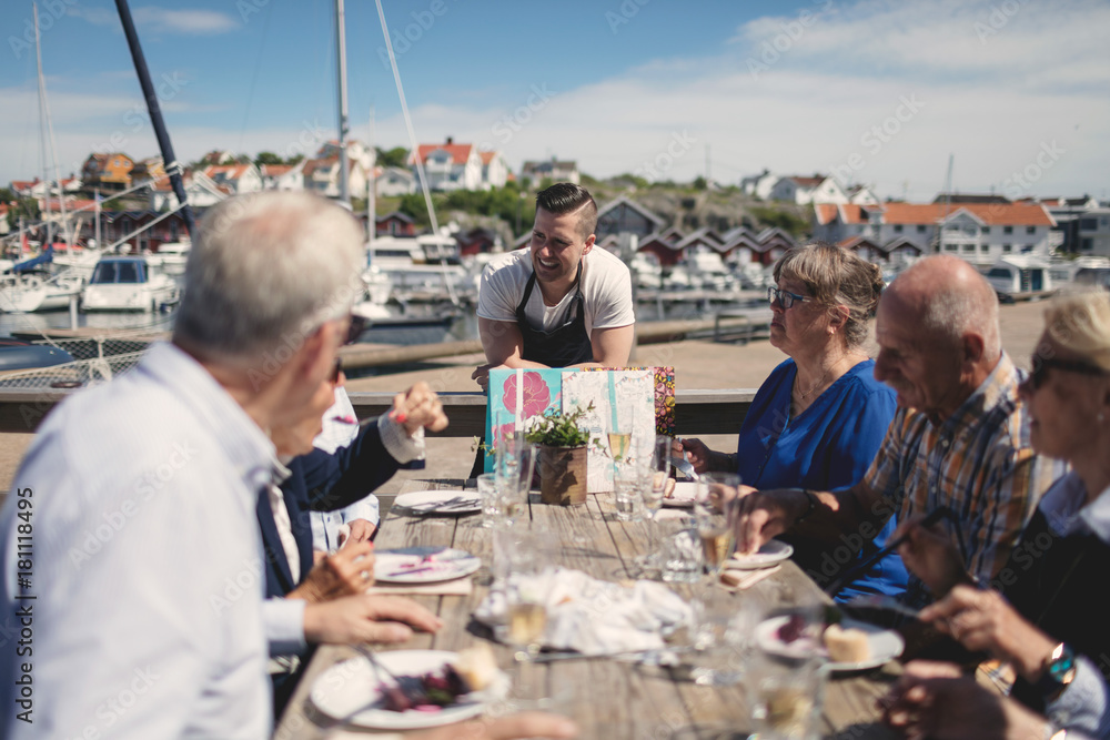 Waiter talking to senior people having lunch at outdoor restaurant Waiter talking to senior people having lunch at outdoor restaurant