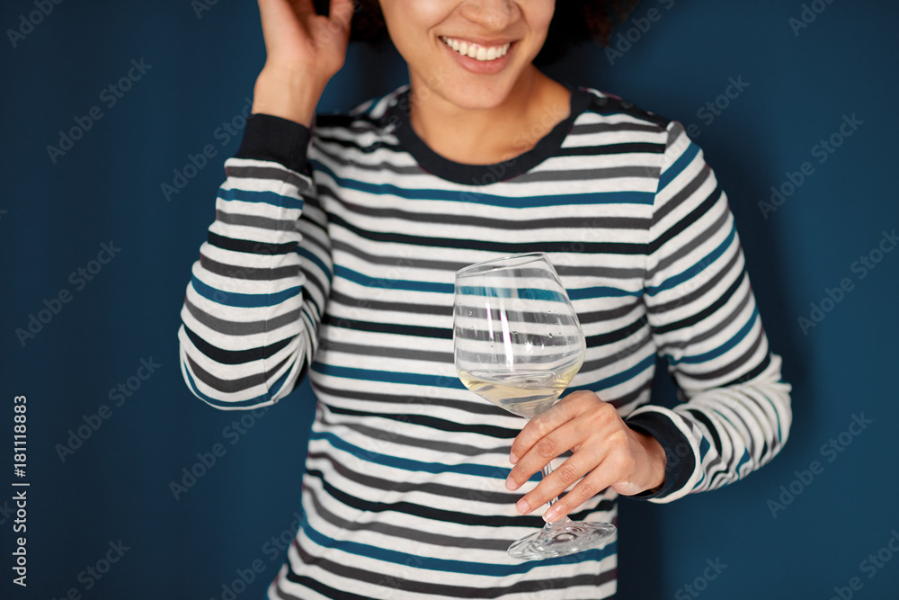 Portrait of mixed race woman holding glass of wine. Blue wall in background Portrait of mixed race woman holding glass of wine. Blue wall in background