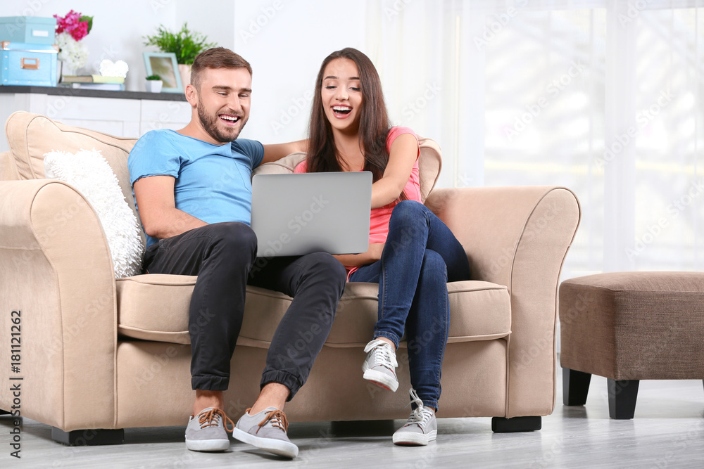 Young couple with laptop on sofa at home