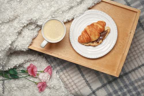 Tasty breakfast with croissant on bed
