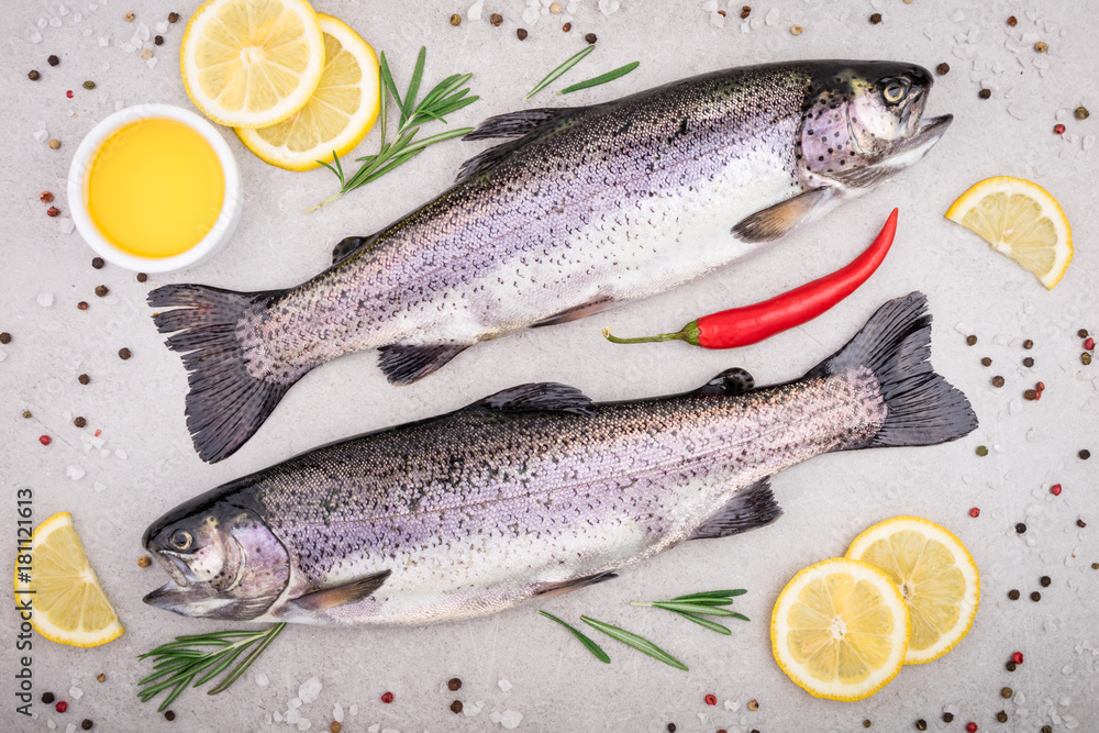Fresh fish. Trout with salt, lemon and spices on gray background. Cooking fish with herbs. Top view Fresh fish. Trout with salt, lemon and spices on gray background. Cooking fish with herbs. Top view