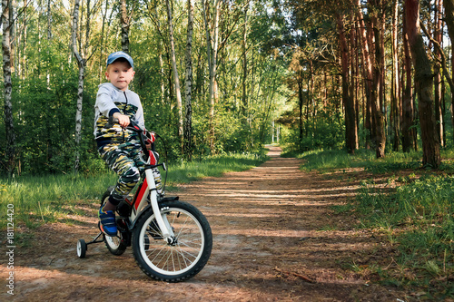 child on a bicycle in the forest in early morning. Boy cycling outdoors in helmet