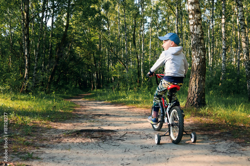 child on a bicycle in the forest in early morning. Boy cycling outdoors in helmet
