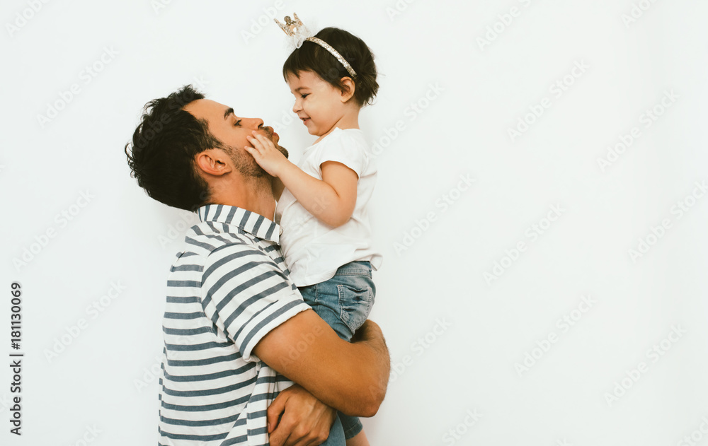 Funny dad and pretty daughter play and cuddle together against white background. Happy sincere relationship of parent and child. Family moments of father and toddler girl's birthday. Parenthood care. Funny dad and pretty daughter play and cuddle together against white background. Happy sincere relationship of parent and child. Family moments of father and toddler girl's birthday. Parenthood care.