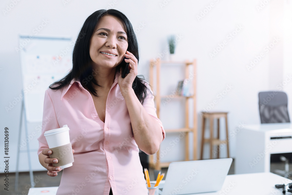 Happy business lady. Delighted female person expressing positivity and holding paper cup while having break