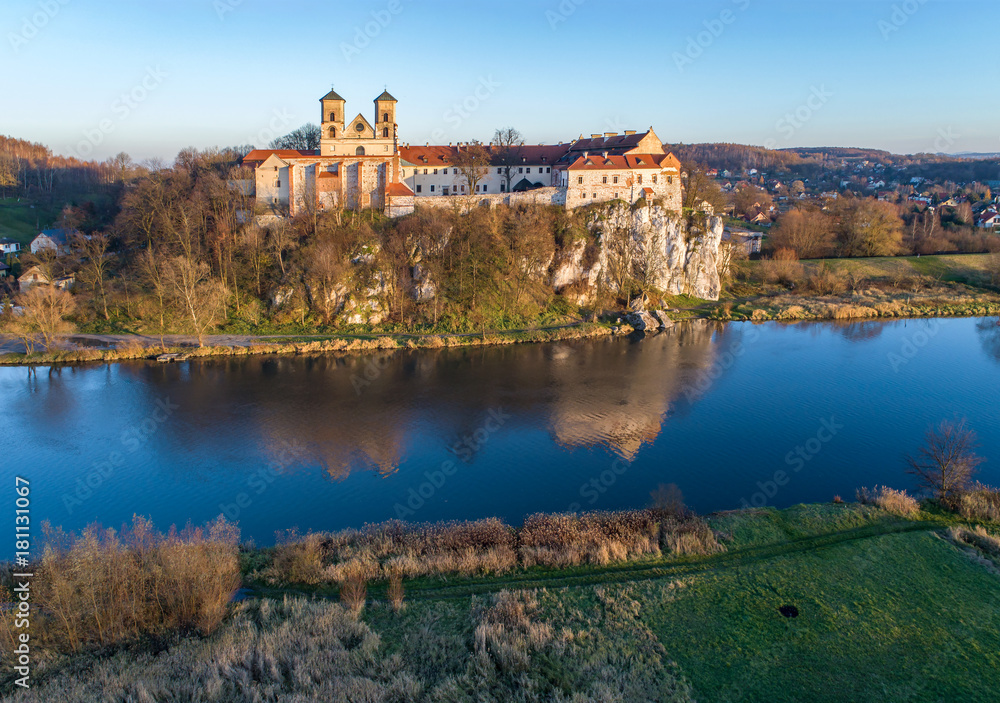 Tyniec near Krakow, Poland. Benedictine abbey on the rocky cliff and its reflection in Vistula River. Aerial view in fall in sunset light