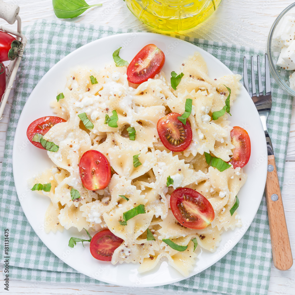 Pasta salad with tie pasta, feta cheese, cherry tomatoes, mustard and basil, top view, square format Pasta salad with tie pasta, feta cheese, cherry tomatoes, mustard and basil, top view, square format