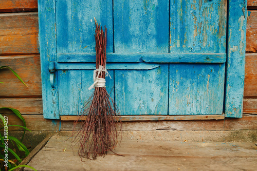 An old broom on the background of a blue antique wooden door