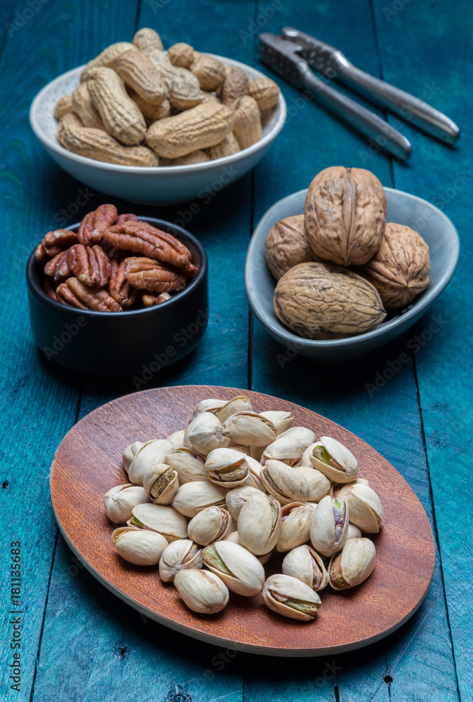 Peanuts pistachios walnuts and pecans on petrol wood Peanuts pistachios walnuts and pecans on petrol wood