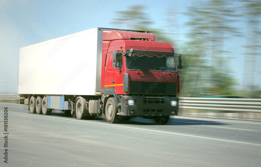 Freight truck is driving along empty road at high speed with the lights on, on a blurry background. Cargo transportation concept. Freight truck is driving along empty road at high speed with the lights on, on a blurry background. Cargo transportation concept.
